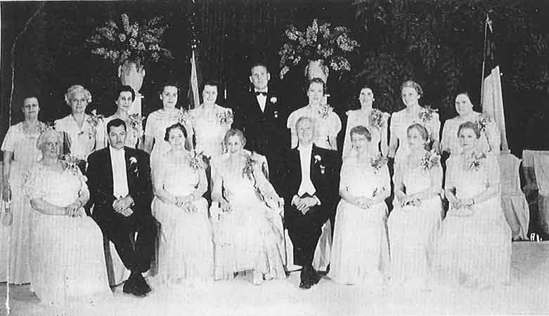 A black and white photo of a group of people in formal attire.