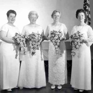 A group of women in white dresses posing for a photo.