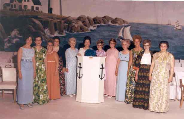 A group of women in dresses posing for a picture.