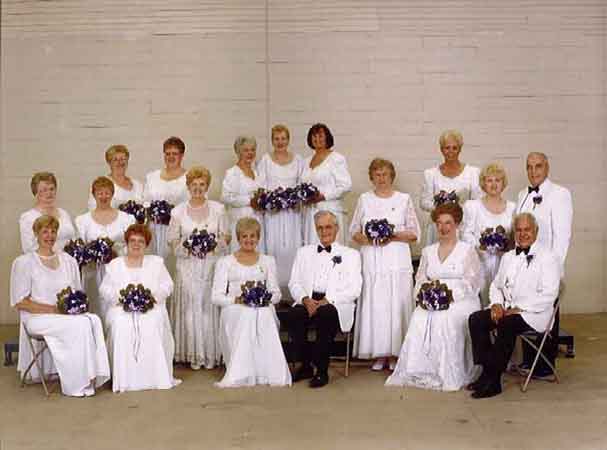 A group of older people in white dresses posing for a picture.