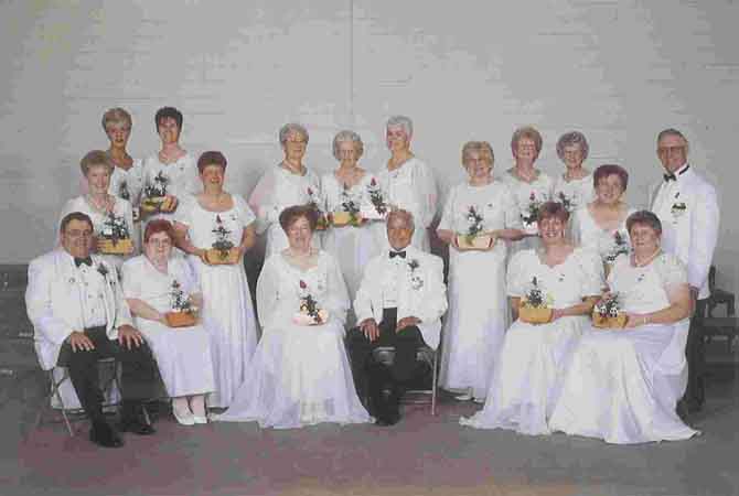 A group of people in white dresses posing for a picture.