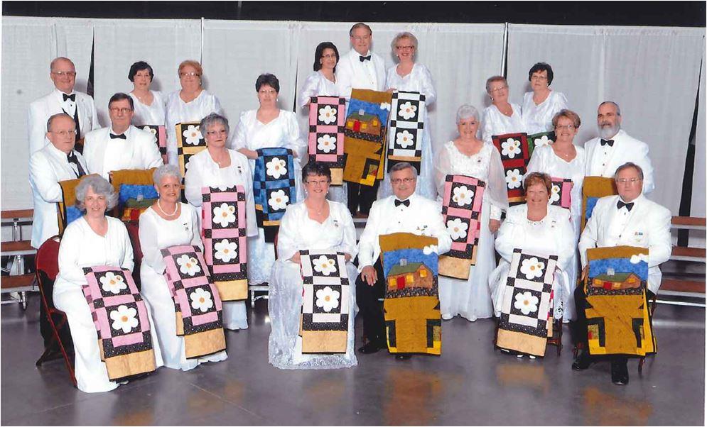 A group of people posing for a photo with their quilts.