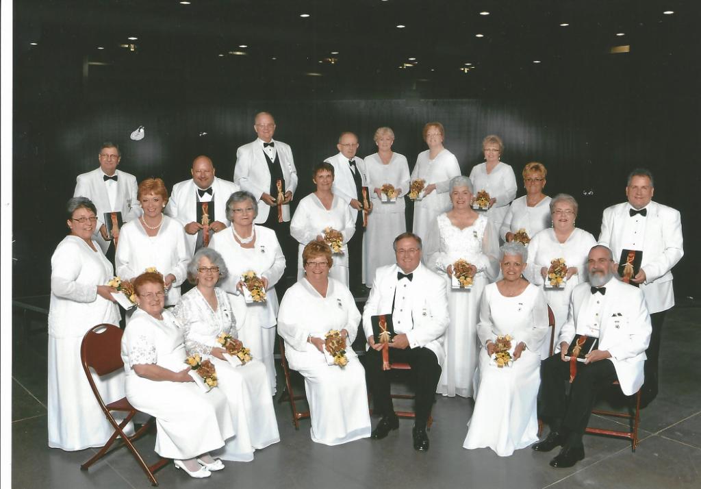 A group of people in white tuxedos posing for a picture.
