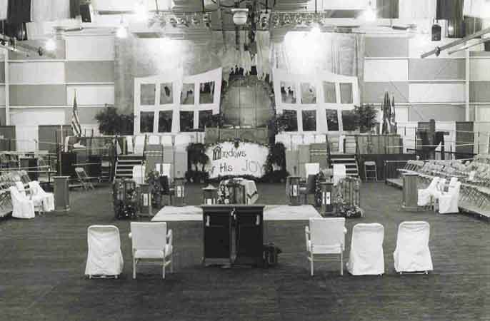 A black and white photo of a room with tables and chairs.