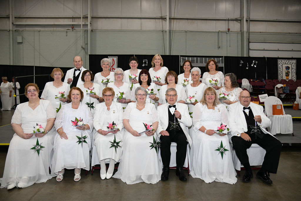 A group of people in white tuxedos posing for a photo.
